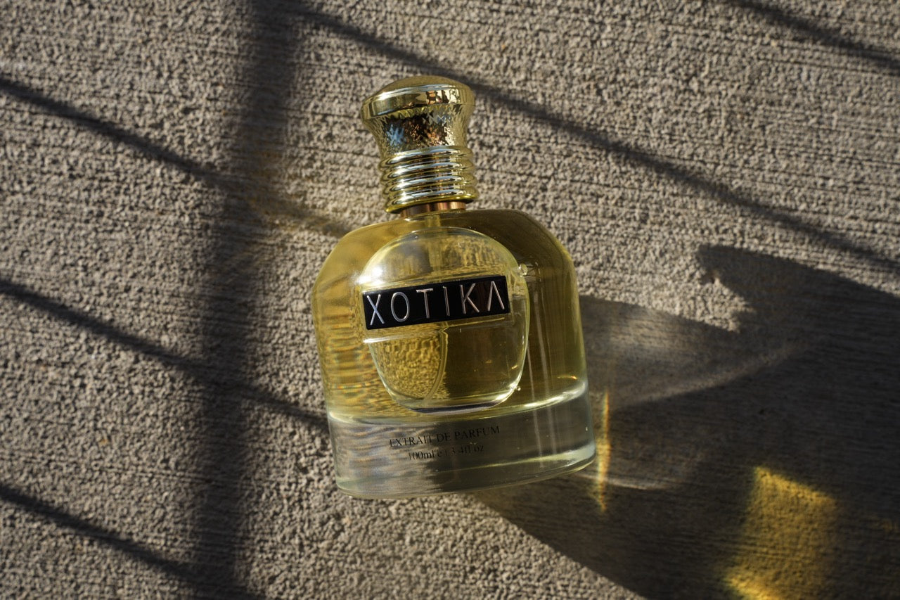Xotika perfume bottle on a textured surface with shadows