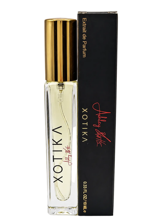 Xotika Extrait de Parfum 10ml bottle with a gold cap next to its black packaging box featuring gold and red text.